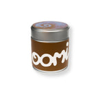 A cylindrical metal tin candle with a brown paper label featuring the white stylized text 'oomi' and a silver lid, shown on a plain white background. This metal tin contains 40 grams of Hojicha Powder.